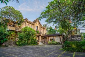 un vecchio edificio con un albero di fronte di Purana Suite Ubud ad Ubud