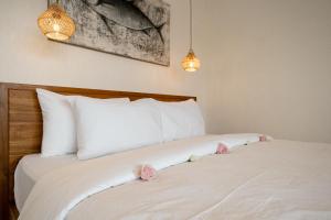 a bed with white sheets and pink roses on it at Brand-New Loft Balangan Village in Badung