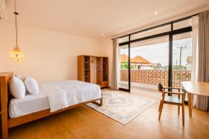 a bedroom with a bed and a table and a window at Brand-New Loft Balangan Village in Badung