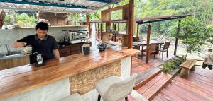 a man standing at a bar on a deck at Puunee Wild River Villa's Borobudur in Borobudur