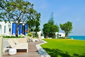 a house with a lawn with a white couch and chairs at Chelona Greece Beachfront! - 2 BR n FREE NETFLIX in Khao Tao