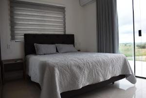 ein Schlafzimmer mit einem Bett mit einer weißen Bettdecke und einem Fenster in der Unterkunft Live the Mar Adentro experience in Santa Cruz de la Sierra + 21 Fotos