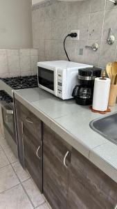 a microwave sitting on top of a kitchen counter at Departamento familiar cerca del aeropuerto in Ezeiza +4 photos