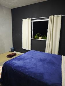 a bedroom with a blue bed and a window at Garden Room Comfort in Garanhuns
