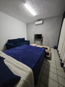a bedroom with a blue bed and a couch at Garden Room Comfort in Garanhuns