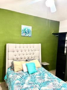 Cama en habitación con pared verde en Departamento Zona Diamante, en Barra Vieja