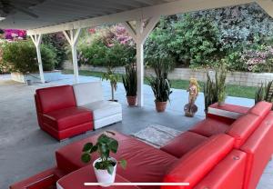 a red couch and chairs on a patio with plants at Suburban oasis home in Monterey Park