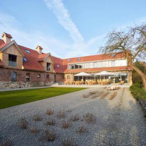 een groot bakstenen gebouw met tafels en stoelen ervoor bij meinwolfsburg hotel auf dem rittergut vormals Yard Boarding Hotel in Wolfsburg