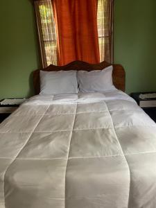 a white bed with white pillows and an orange curtain at Seaview Guesthouse Apt#1 in Bank Level