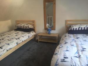 een slaapkamer met 2 bedden, een tafel en een spiegel bij Isambard Cottage in Weymouth