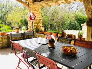 a wooden table with a bowl of fruit on a patio at Le Mas Brantôme in Brantôme