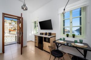 a living room with a table with chairs and a television at Agkyra Studio in Symi