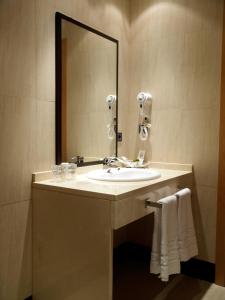 a bathroom sink with a mirror and a towel rack at Hotel Isur Llerena in Llerena