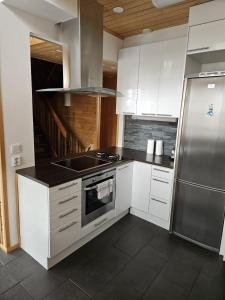 a kitchen with white cabinets and a stainless steel refrigerator at Levi Happi in Kittilä