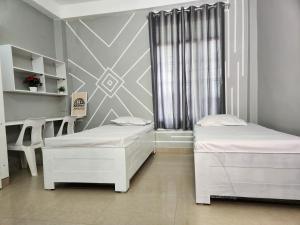 a room with two beds and a desk and a window at Akshay BnB & HomeStay in Lucknow
