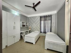 a bedroom with two beds and a desk and a ceiling fan at Akshay BnB & HomeStay in Lucknow +30 photos