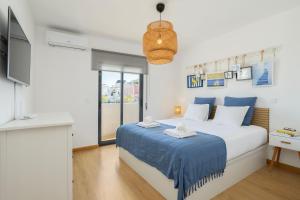 a bedroom with a bed with blue sheets and a tv at Central Olhão, 2min Island Ferry, Pool, Private Parking in Olhão