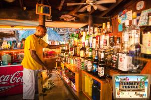 Un uomo in piedi dietro un bancone in un pub di Bananarama Dive & Beach Resort a West Bay