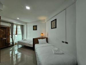 a bedroom with two beds and a lamp on the wall at Madugu Service Apartment in Chiang Mai