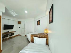 a hotel room with a bed and a desk at Madugu Service Apartment in Chiang Mai