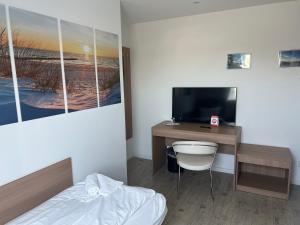 a bedroom with a desk with a tv and a bed at Hotel am Schlosspark Superior in Putbus