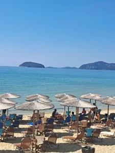 a group of people sitting on a beach with umbrellas at Vintage villa in Paleo Tsifliki