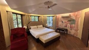 a bedroom with a bed and a red chair at Aayush Resort Karjat in Kālundri