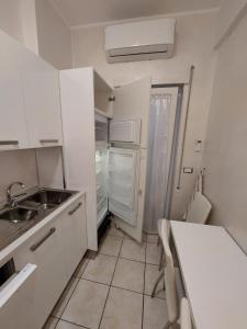a white kitchen with a sink and a refrigerator at DOMuS APA in Ladispoli +5 photos