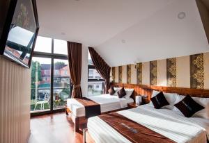 a hotel room with two beds and a large window at Bảo Anh Villa Đà Lạt in Da Lat