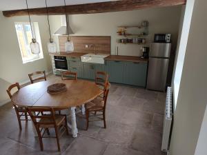 a kitchen with a table and chairs and a refrigerator at La Ferme De la baie in Favières