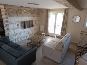 a living room with two couches and a brick wall at La Ferme De la baie in Favières