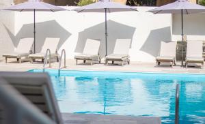 a group of chairs and umbrellas next to a swimming pool at NEFELI by Evita's Resort in Poros