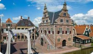 a large brick building with a tower on top of it at Huisje Britt met grote tuin en veel privacy in Dirkshorn