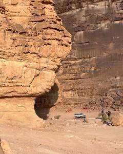 Un jeep estacionado en el desierto junto a un acantilado en Wadi rum Mahmoud tours, en Wadi Rum
