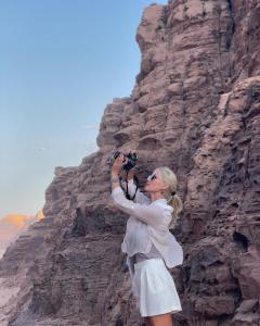 una mujer tomando una foto de una montaña con una cámara en Wadi rum Mahmoud tours, en Wadi Rum