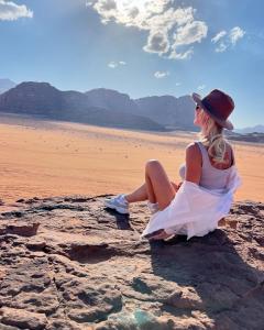 una mujer sentada en una roca en el desierto en Wadi rum Mahmoud tours, en Wadi Rum