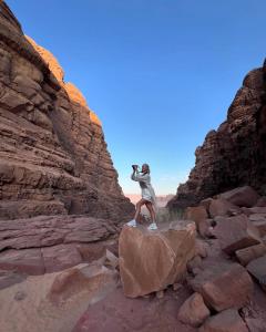 un hombre parado en una roca en un cañón en Wadi rum Mahmoud tours, en Wadi Rum