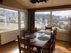 a dining room with a table and chairs and windows at Chalet Belfahy in Belfahy