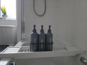 three black bottles sitting on a shelf in a bathroom at Bridge View Stayz in Plymouth +43 photos
