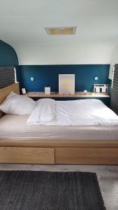 a large bed with a wooden frame in a bedroom at Wohnwagen auf Tierschutz Landhof inmitten der Natur in Selmsdorf +16 photos