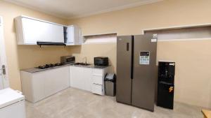 a kitchen with a stainless steel refrigerator and white cabinets at Villa Dalia Puncak M4-3 in Cikundul