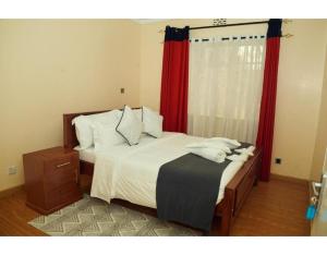 a bedroom with a bed with red curtains at Spacious Town House in Nakuru in Nakuru