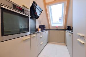a kitchen with white cabinets and a large tv at Brandneues Stadtglanz Apartment in Stuttgart