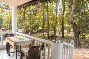 a table and chairs on a porch with trees at Anna Cottages Agonda in Agonda