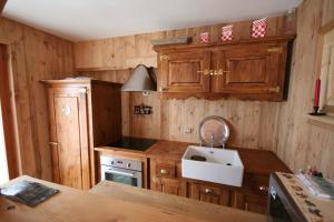 Una cocina con gabinetes de madera y un fregadero. en Charming Alpine studio, en Planvillard