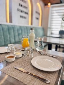 a table with plates and glasses and a bottle of orange juice at Mili Hotel in Berat