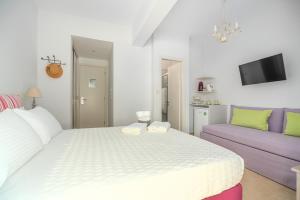 a bedroom with a white bed and a purple couch at Arolithos in Spetses