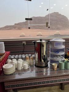 Gakleen luxury camp في العقبة: كاونتر مع أكواب وصحون وآلة صنع القهوة