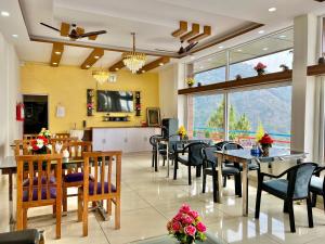 a dining room with tables and chairs and a large window at Dhurva Hotel and Resort in Naugaon