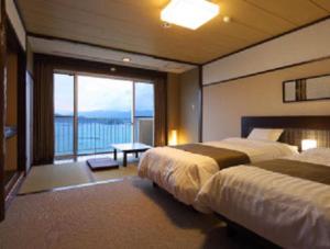 Una habitación de hotel con dos camas y balcón. en 宿毛リゾート椰子の湯, en Sukumo